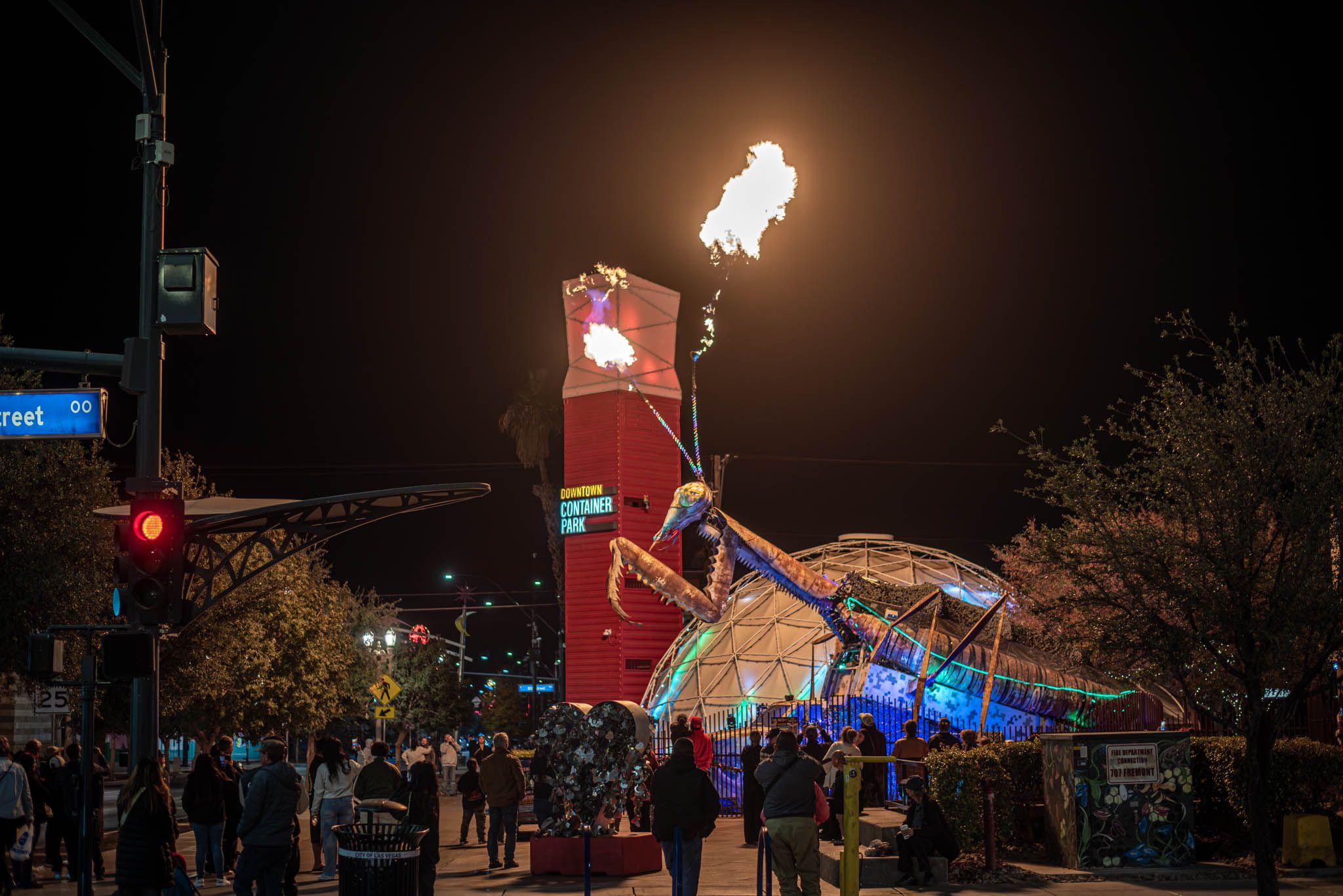 People surrounded by a mechanical pray mantis shooting fire out of its antennae